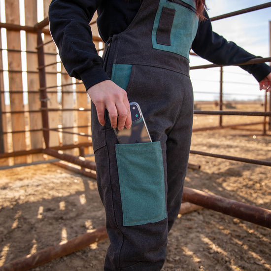 Person wearing a black with teal accent overalls in an outdoor setting