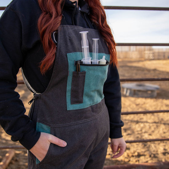 Person wearing a black and teal work outfit with a field background