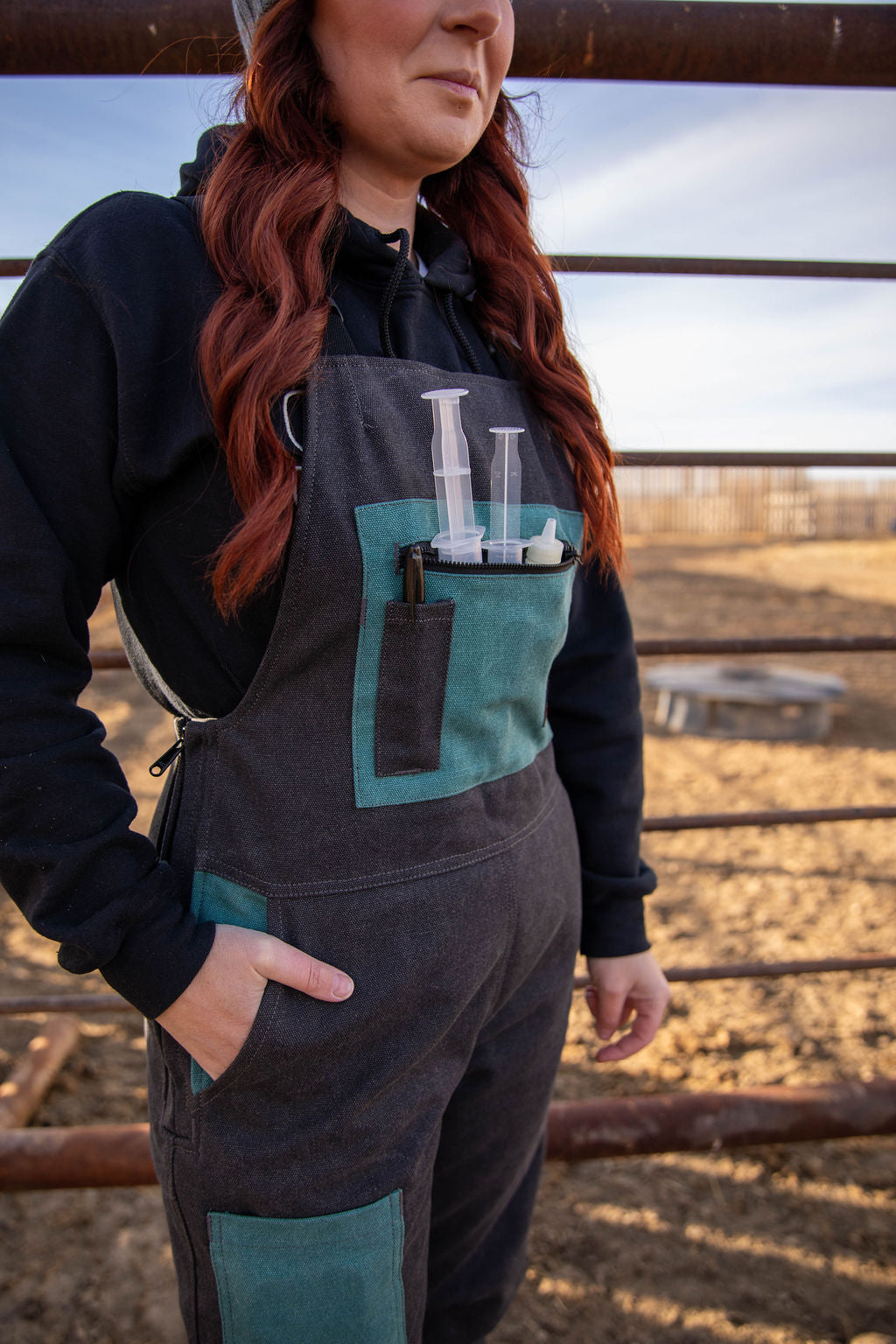 Person wearing a black and teal work outfit with a field background