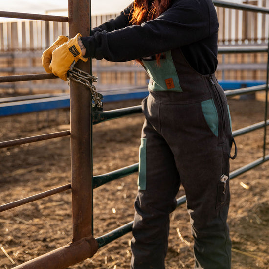 Person working with a chain on a metal fence in an outdoor setting