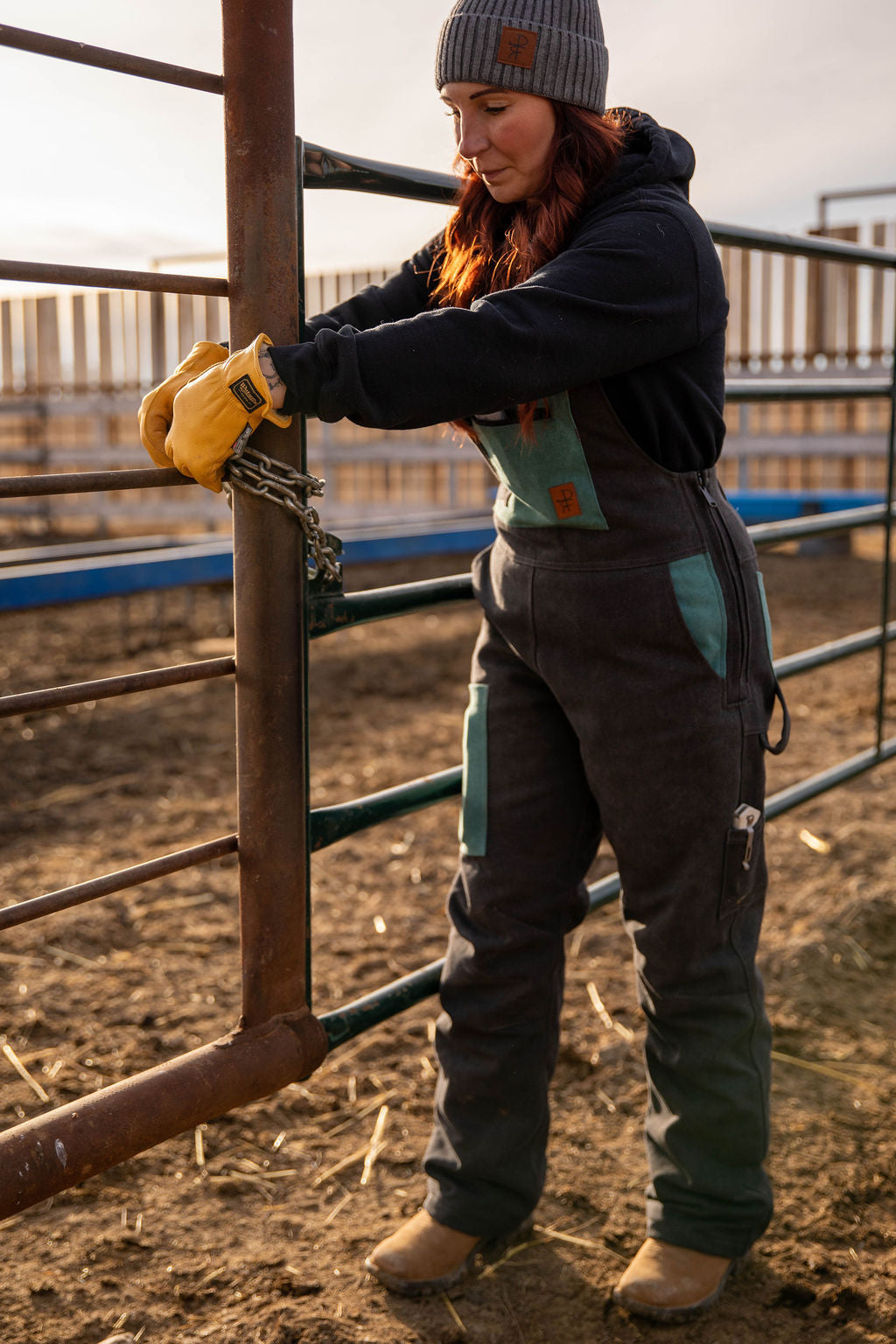 Person working with a chain on a metal fence in an outdoor setting