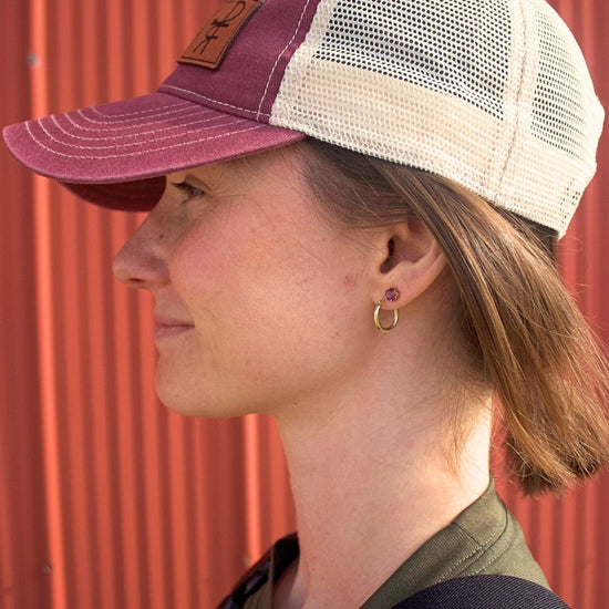 Person wearing a maroon and beige cap against a red corrugated metal background