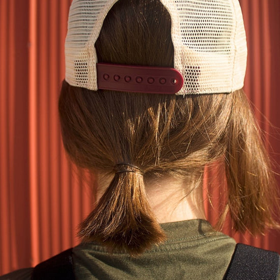 Person wearing a white cap with a red strap on a red background