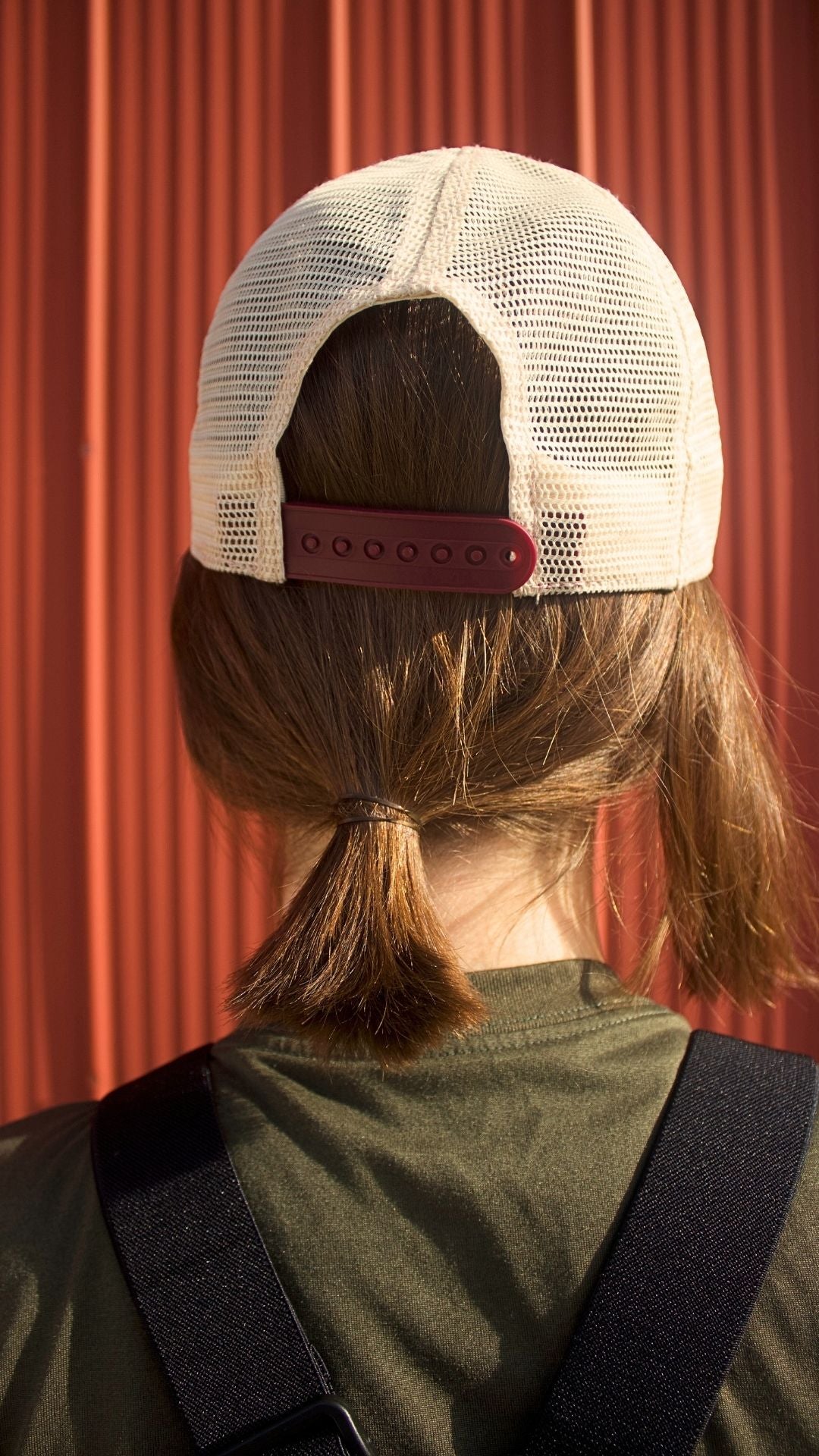 Person wearing a white cap with a red strap on a red background