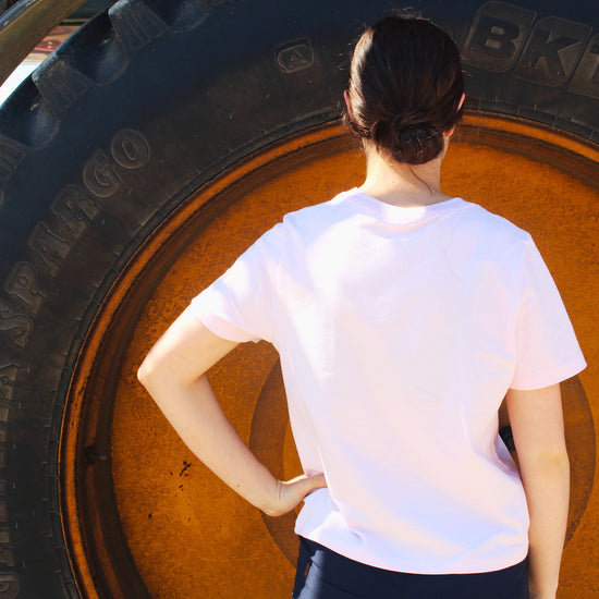Person in a pink shirt standing in front of a large tire.