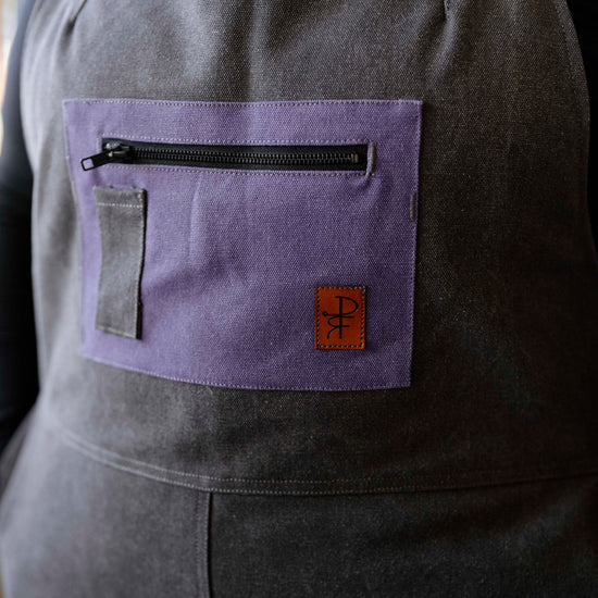 Person wearing grey overalls with purple pocket 