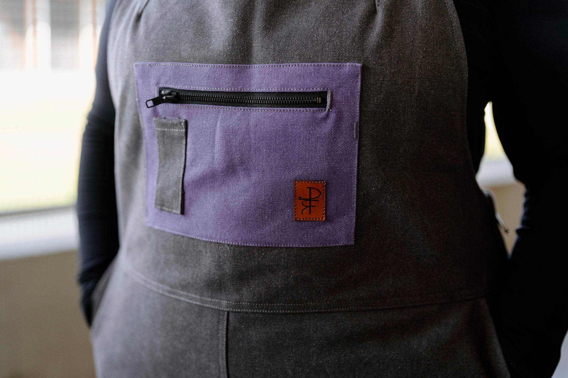 Person wearing grey overalls with purple pocket 