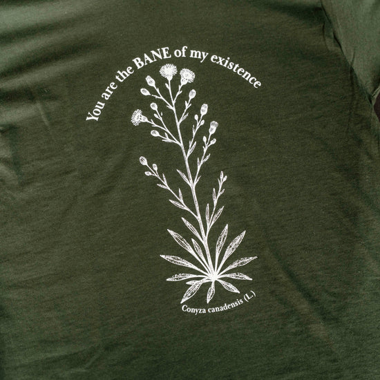 Green t-shirt with white floral design and text on a hanger