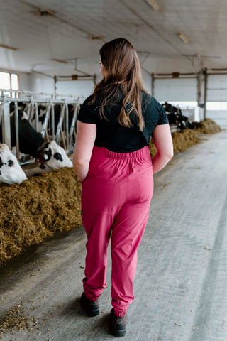 Person walking in a barn with cows and hay bales.