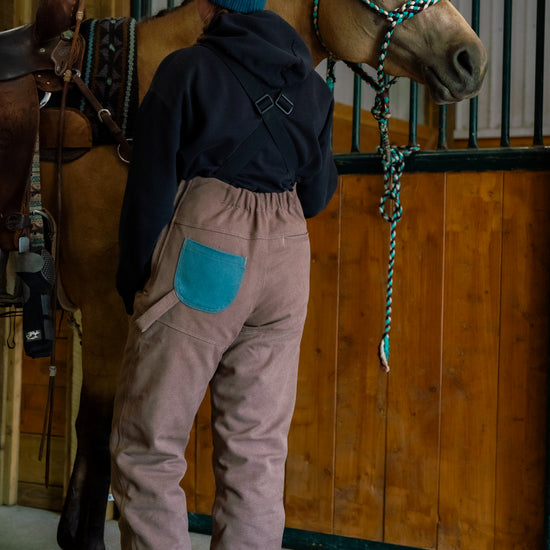 a person wearing brown and turquoise overalls with horse 