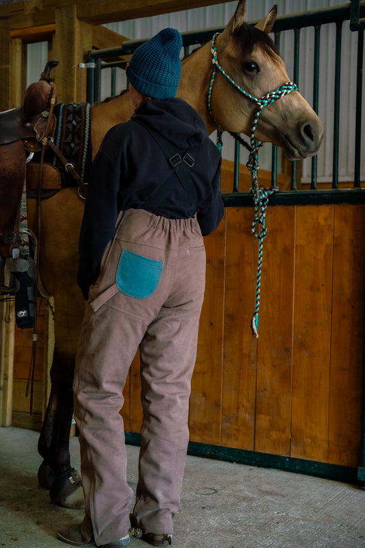 a person wearing brown and turquoise overalls with horse 