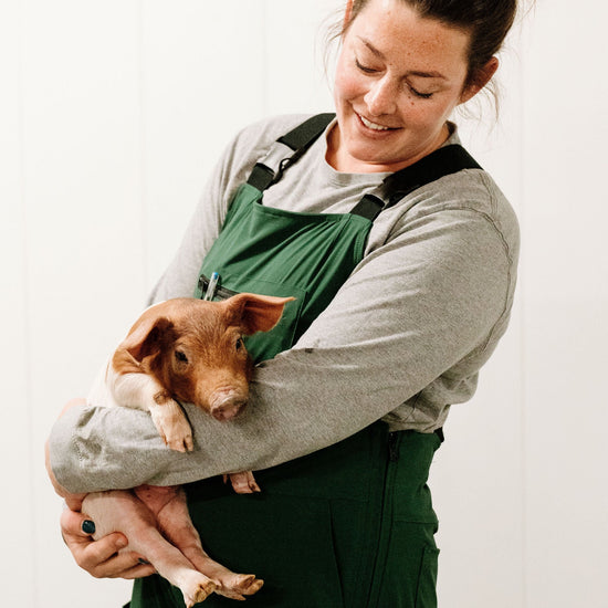 Lady holding pig in green overalls 