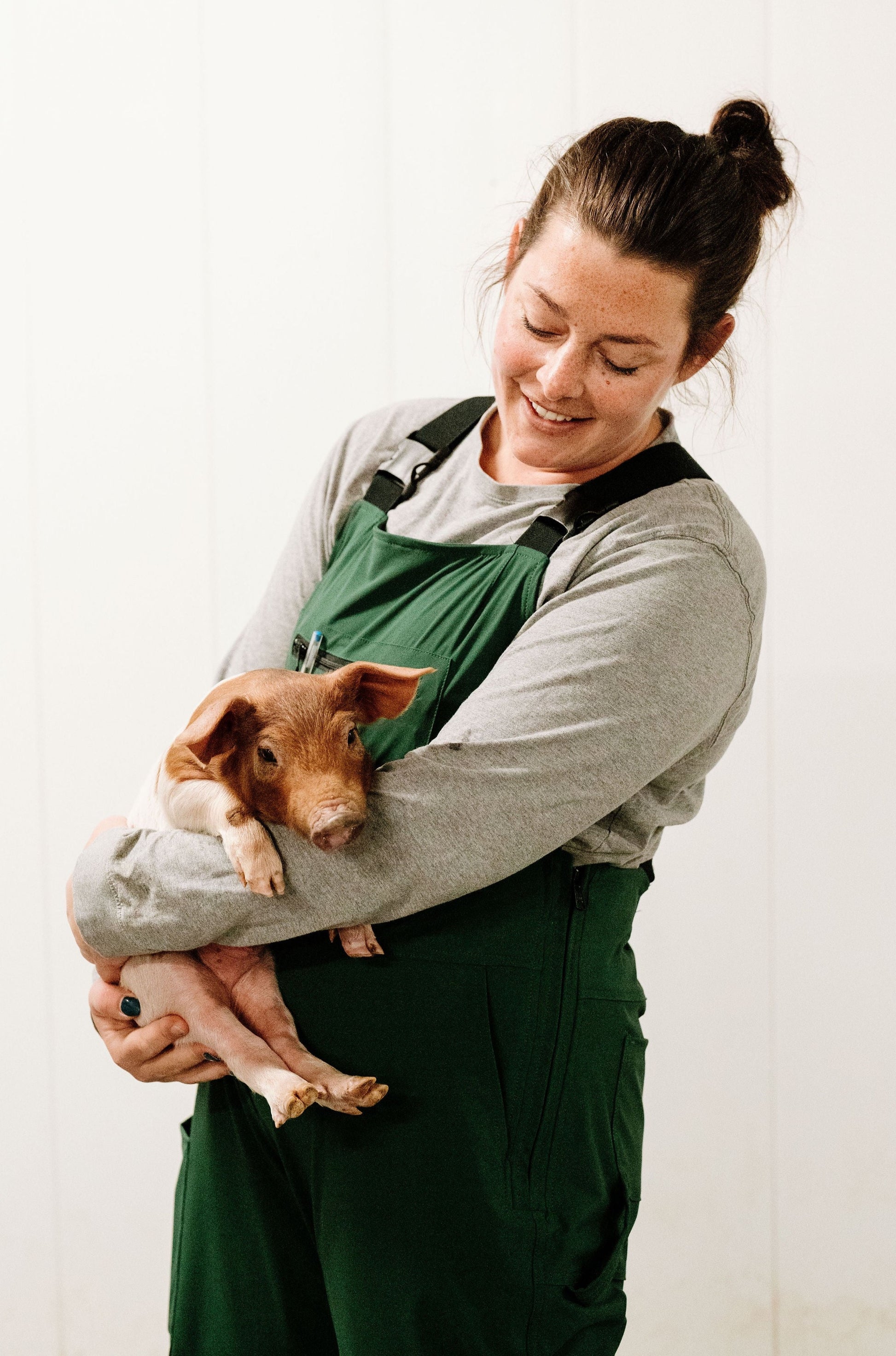 Lady holding pig in green overalls 