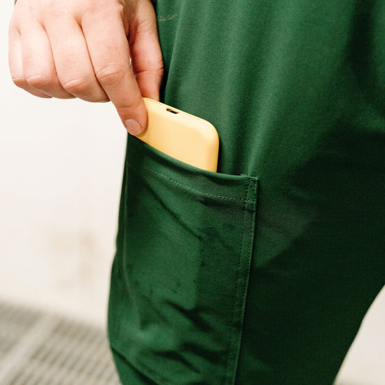Person putting yellow object into dark green overalls