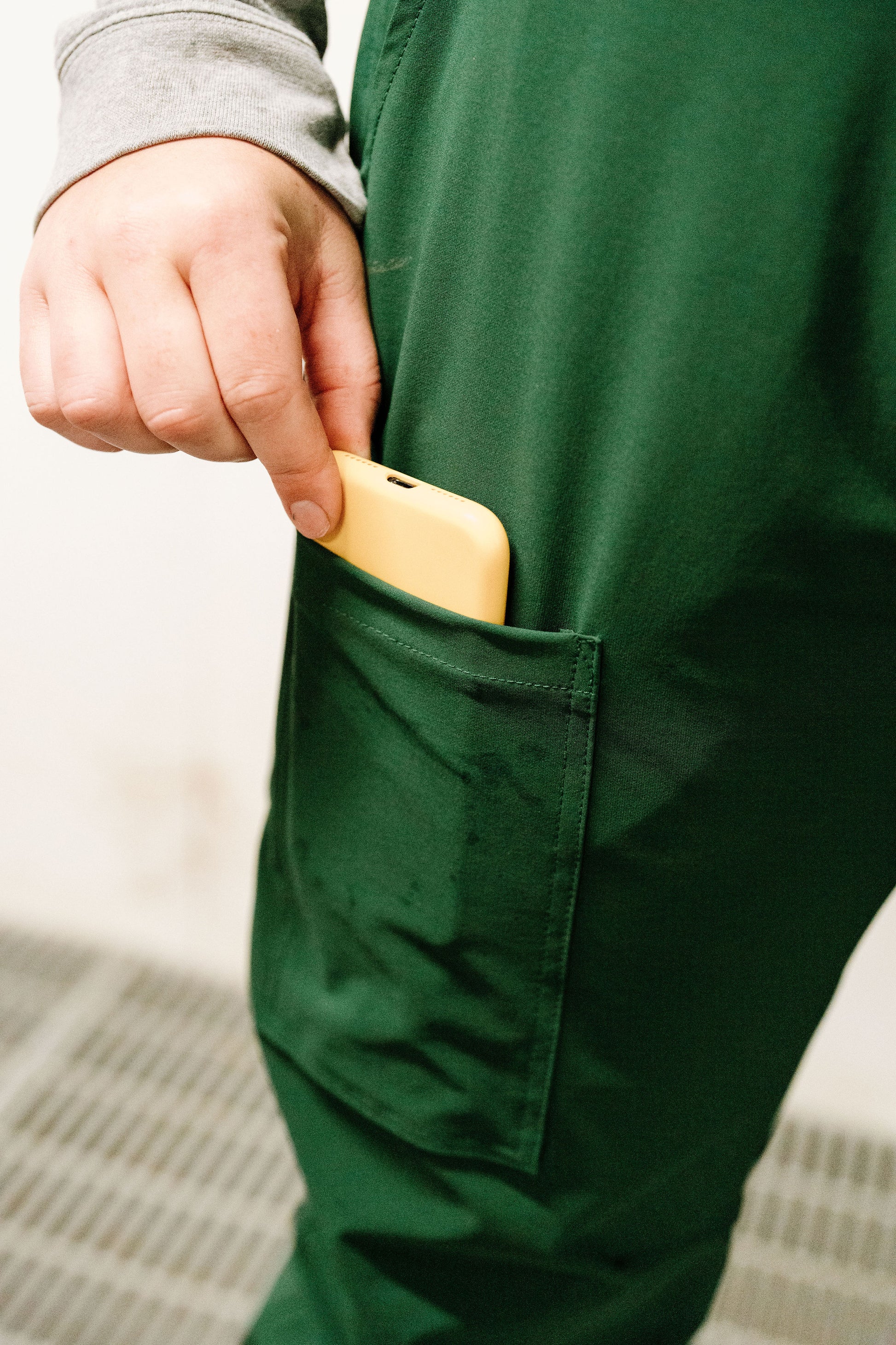 Person putting yellow object into dark green overalls